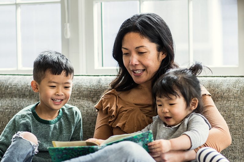 Mother reading to kids on couch